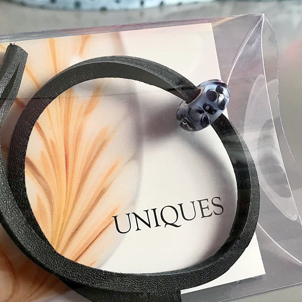 Trollbeads UNIQUES are one-of-a-kind glass beads handmade individually by 100% artisan-owned workshops. This Suzie Q Studio UNIQUES glass bead has beautiful black and white pansies floating on pale blue.