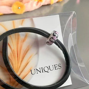 Trollbeads UNIQUES are one-of-a-kind glass beads handmade individually by 100% artisan-owned workshops. This Suzie Q Studio UNIQUES glass bead has a retro-style design in the striking colour-combo of pale pink, black and white!