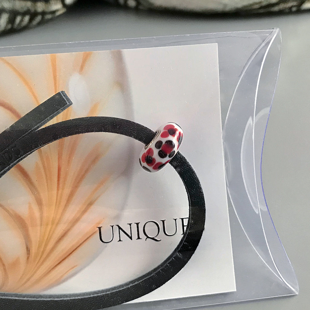  This Suzie Q Studio Trollbeads UNIQUES glass bead bracelet features the powerful and classic color-combo of red, black and white with a black leather bracelet.