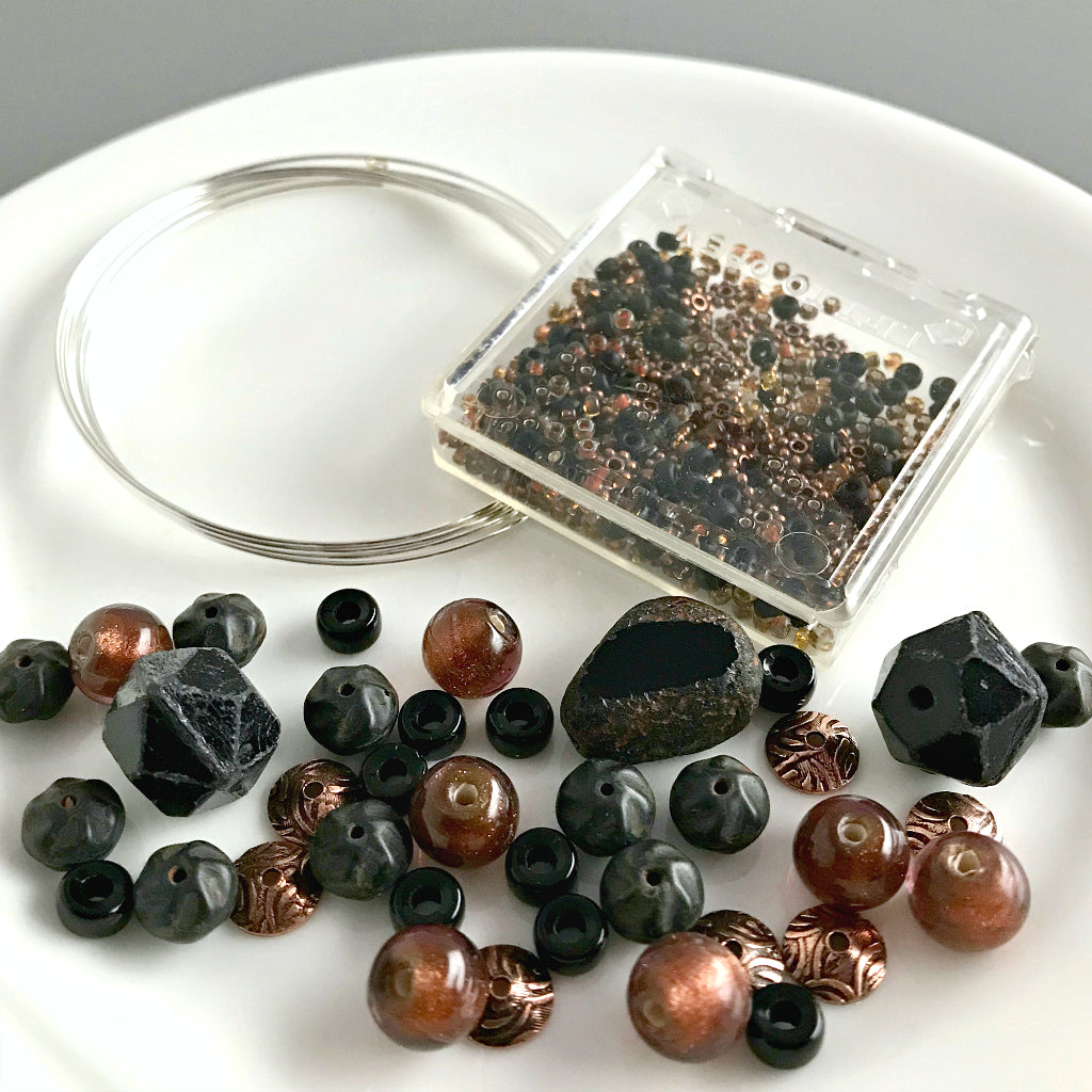 Suzie Q Studio's Serendipity BEAD STEW DIY EASY BRACELET MAKING KITS are limited edition collections of artfully curated premium quality beads and components for you to make a one-of-a-kind bracelet(s). No experience needed!  This "Black Velvet Apricot" kit contains matte and shiny black, sparkly bronze-copper and metallic, antique copper beads.