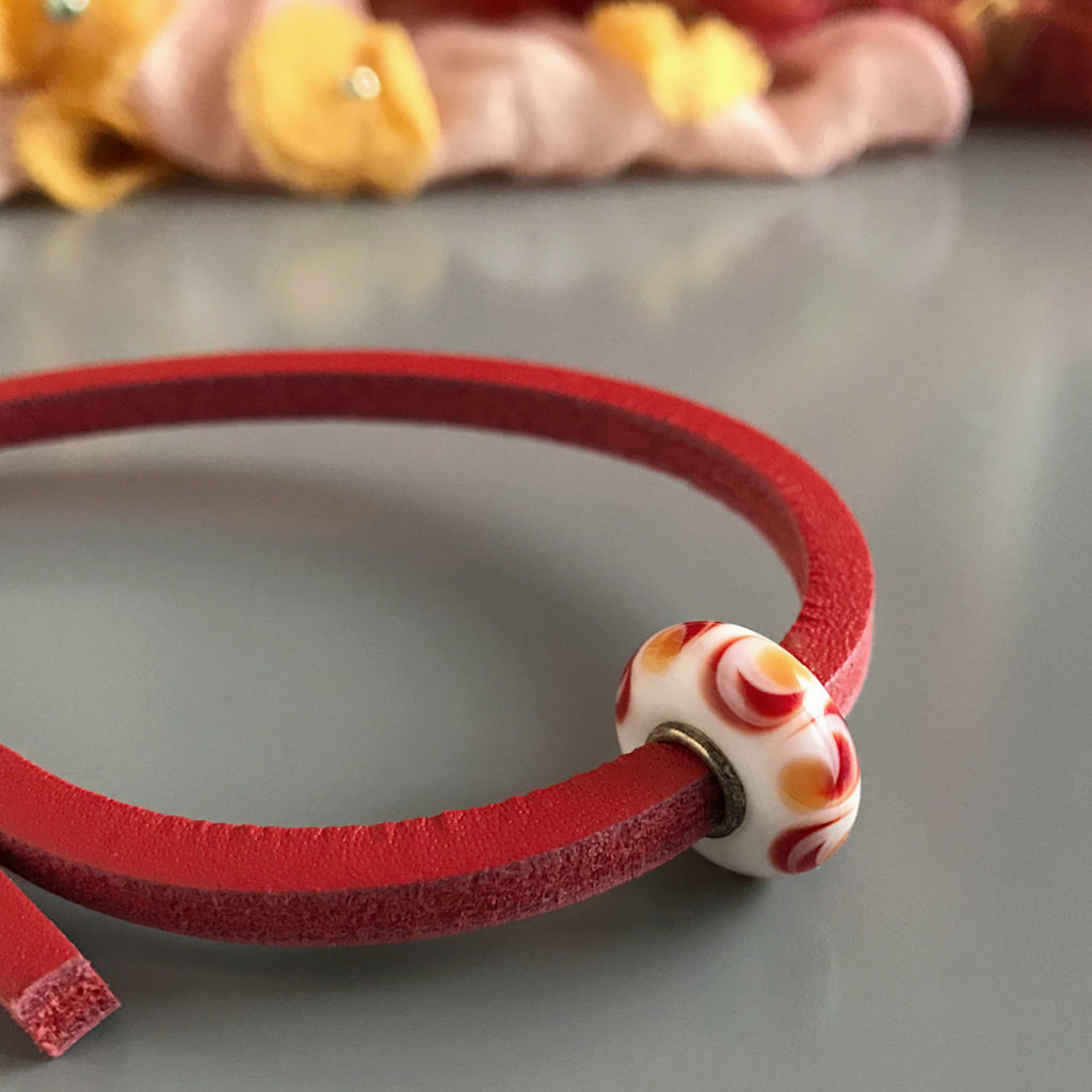 This happy-go-lucky Suzie Q Studio Trollbeads UNIQUES glass bead looks like suns whirling around, and includes a colour-coordinated leather bracelet.