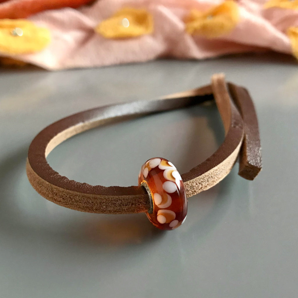 This super-sweet Suzie Q Studio Trollbeads UNIQUES glass bead bracelet looks like scrumptious maple syrup candy that you make on snow and has a leather bracelet.