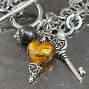 This Suzie Q Studio one-of-a-kind bracelet features a gorgeous, amber-coloured, handblown Italian Murano glass heart, a key charm, as well as Swarovski glass pearl accents and the neutral colours will coordinate with just about any outfit in your closet. 