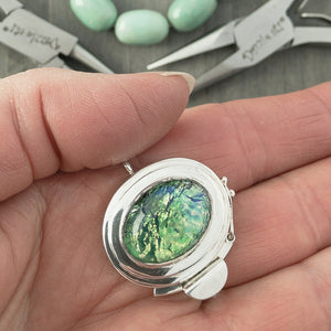 The metallic-effect of the vintage glass cabochon stone in this sterling silver box clasp is called a "harlequin" finish, which is extremely popular, and this blue-green version is exquisite!